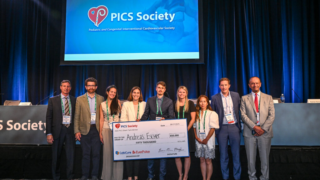 Group on stage holding a giant $50,000 check presented to Andreas Escher at the PICS Society event, sponsored by CobiCure and EverPulse
