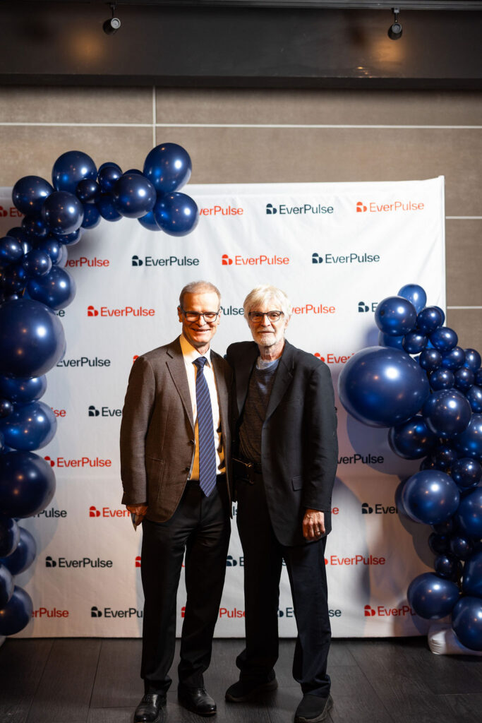 Two men posing in front of the EverPulse branded backdrop at the fundraiser